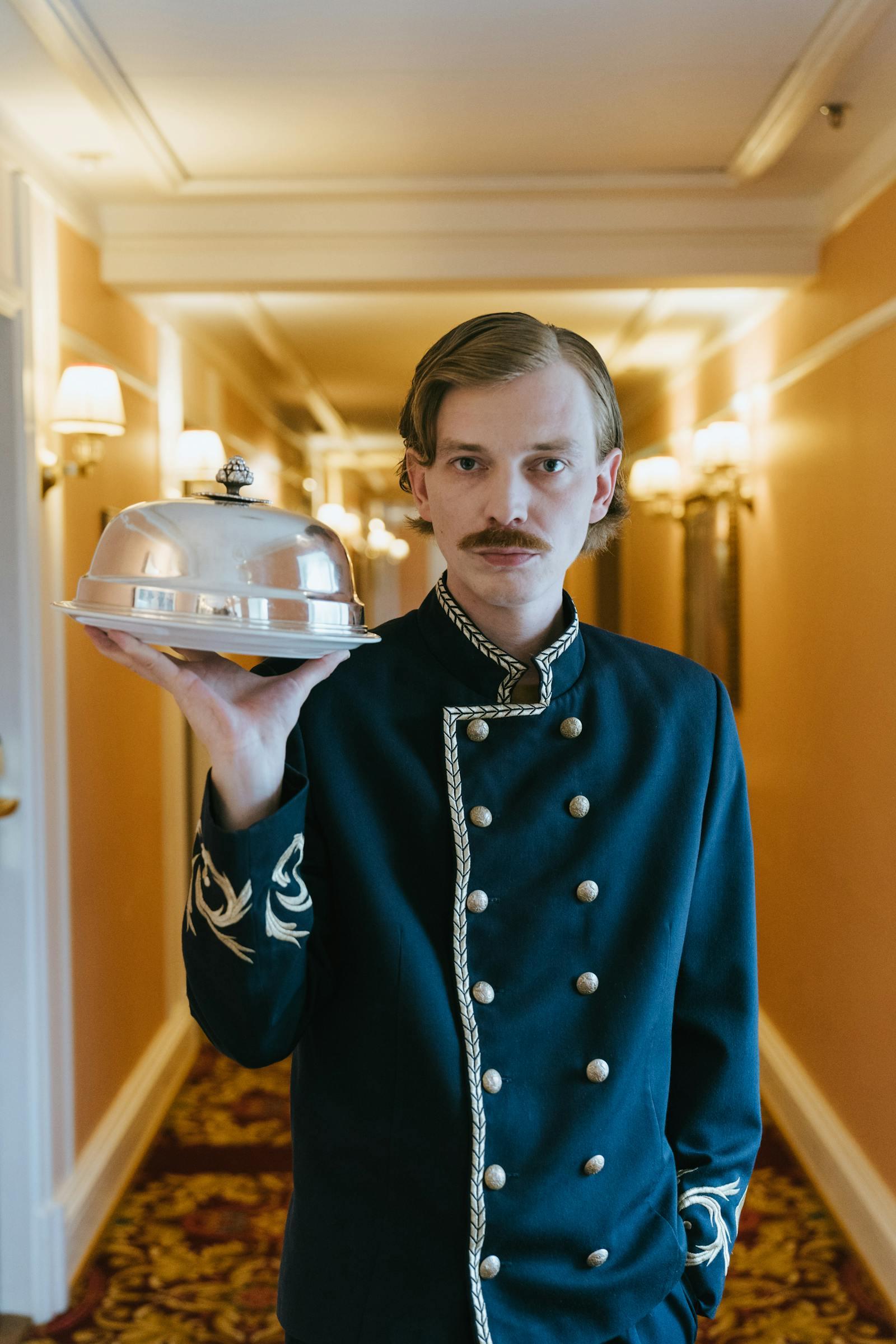 Hotel service staff holding a covered dish